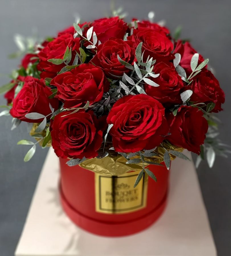 Красные розы с зеленью в шляпной коробке